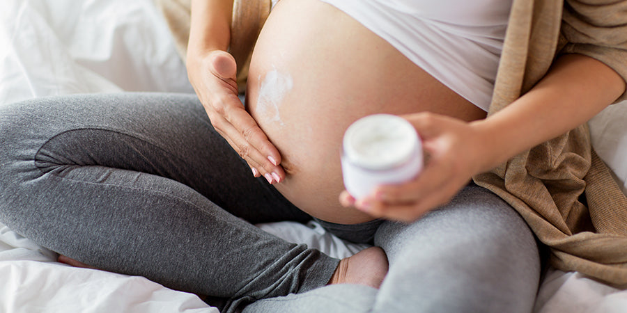 Pregnant woman applying cream to her bump